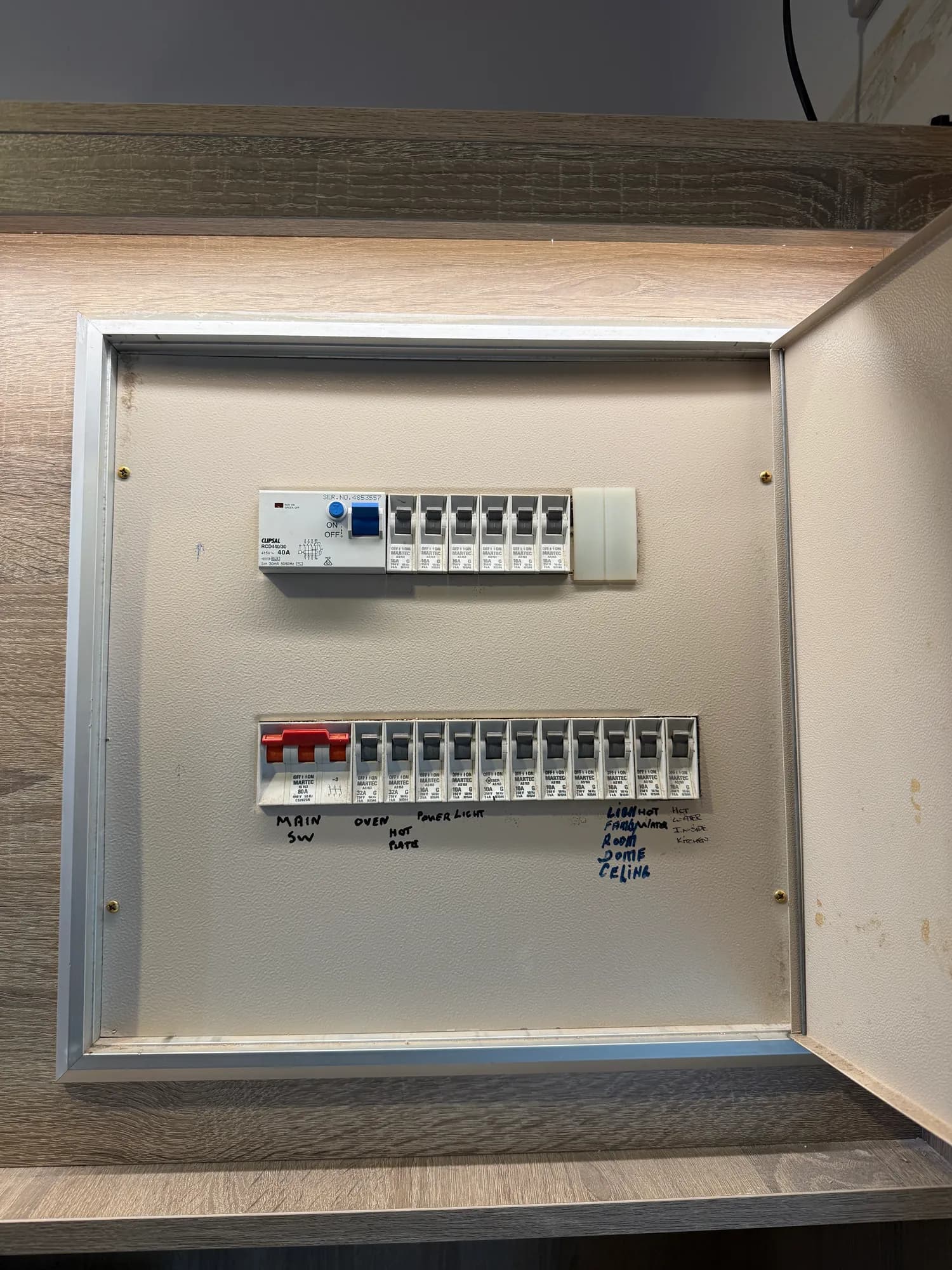 The old board in the same cabinet: a Clipsal safety switch, Martec breakers and handwritten circuit labels