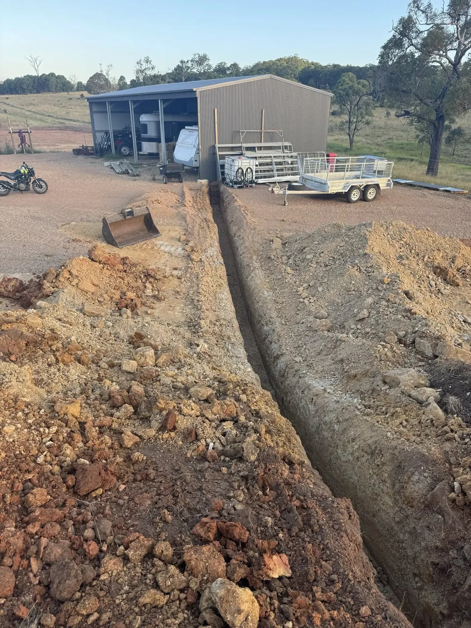 Long-distance underground power run on a rural property. Trenching, conduit laying, and backfill for a new electrical supply to an outbuilding.