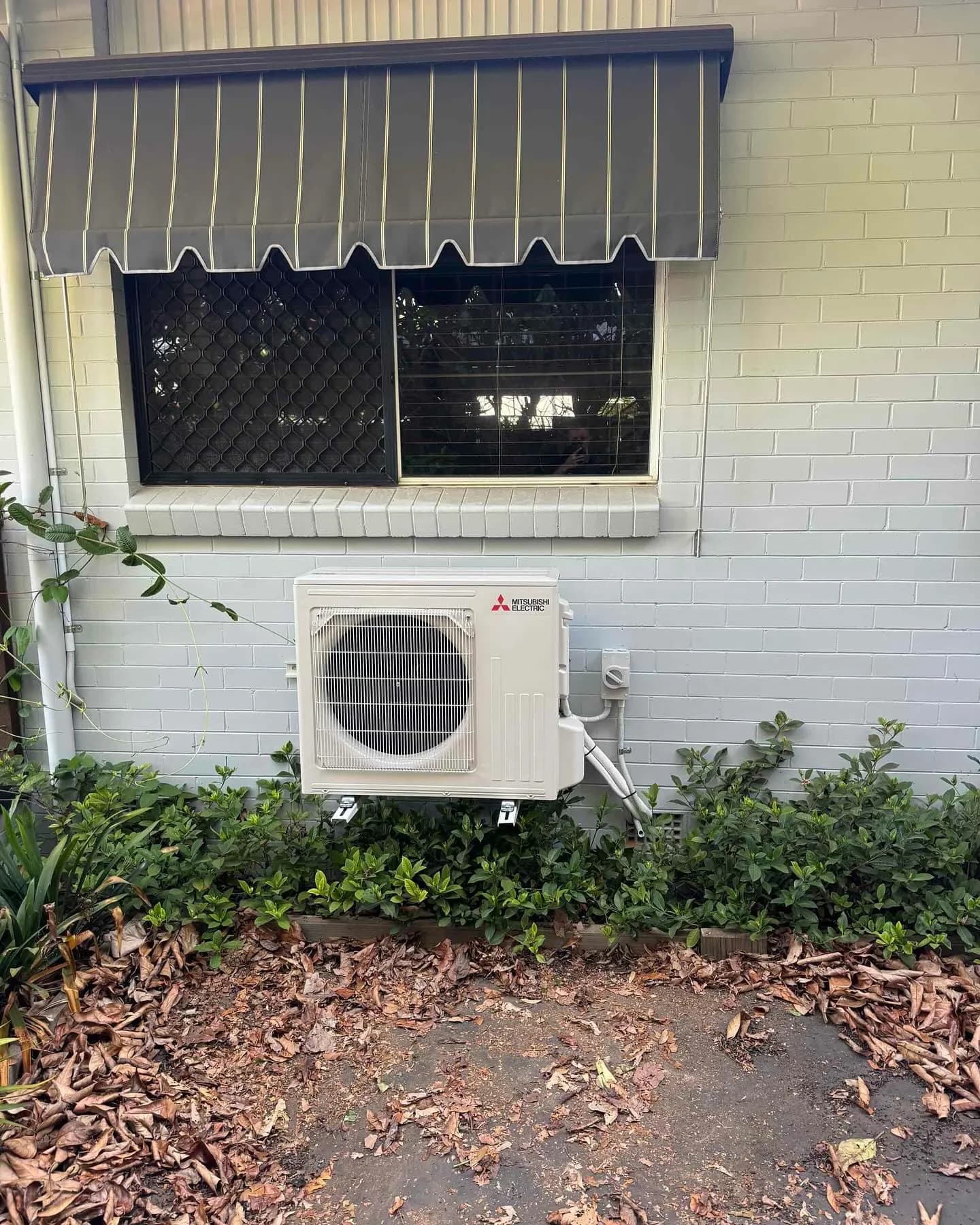 Mitsubishi split system air conditioning — indoor and outdoor units. Wall bracket mounting, clean conduit runs, and neat cable management throughout.