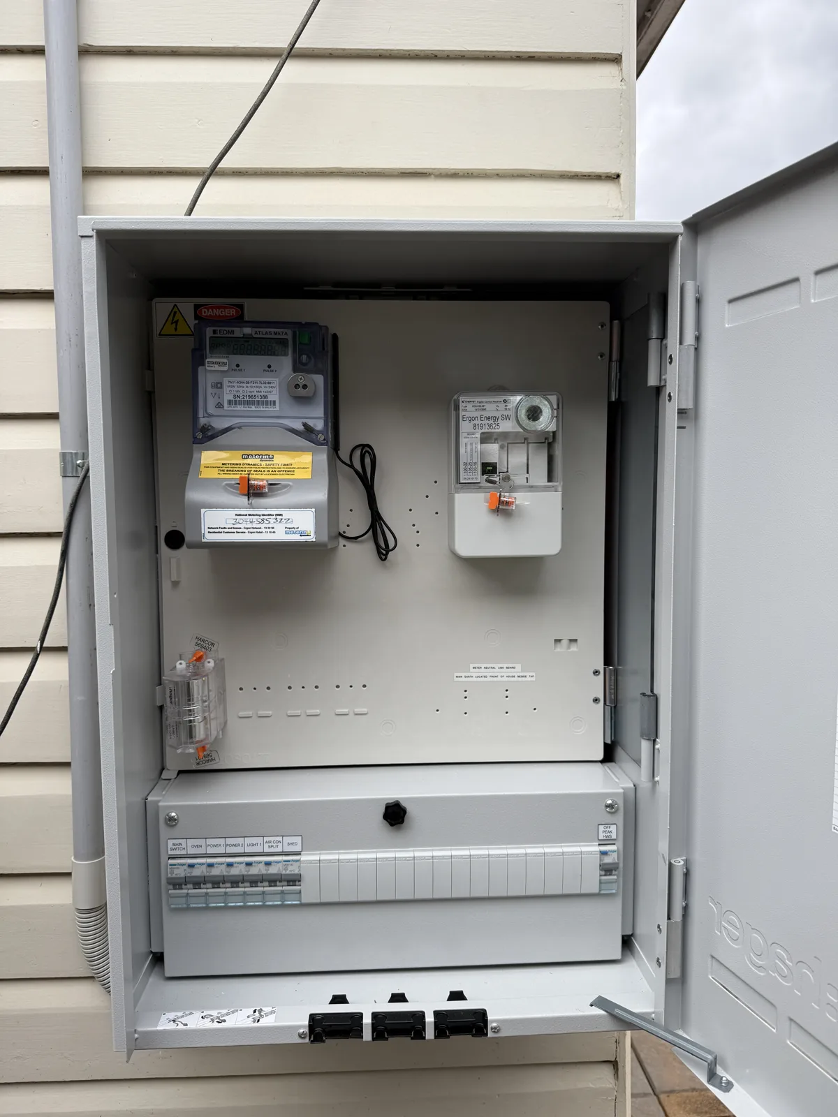 Old flush-mounted meter box in a weatherboard home replaced with a new surface-mounted enclosure, smart metering and full circuit protection. Before and after.